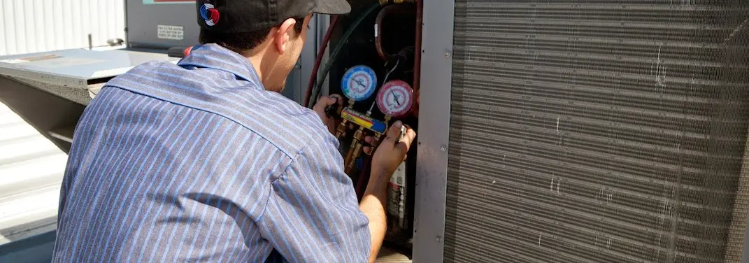 HVAC technician servicing a condenser unit in Whitestown